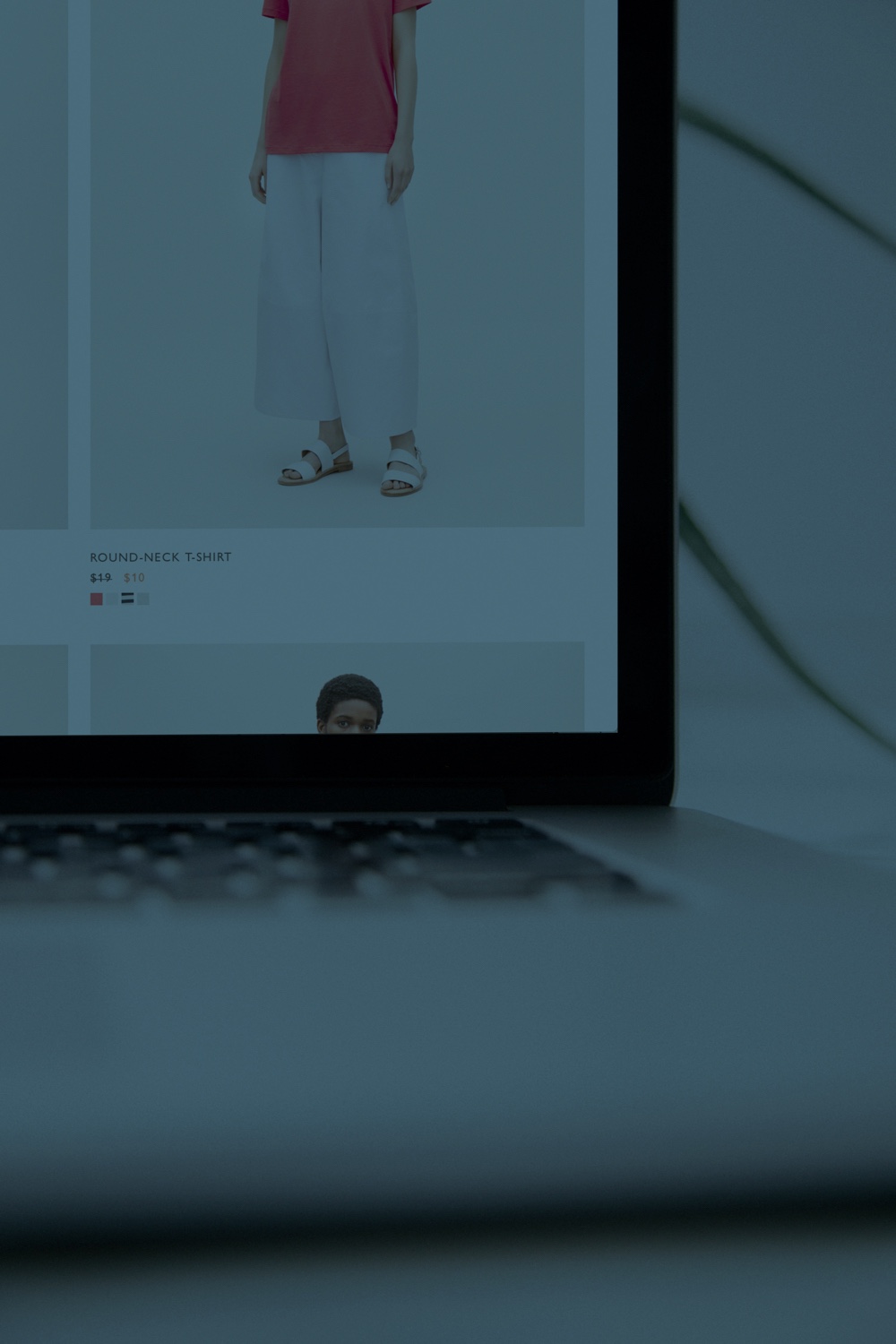 Laptop with online clothing store open, showing a model in white pants.