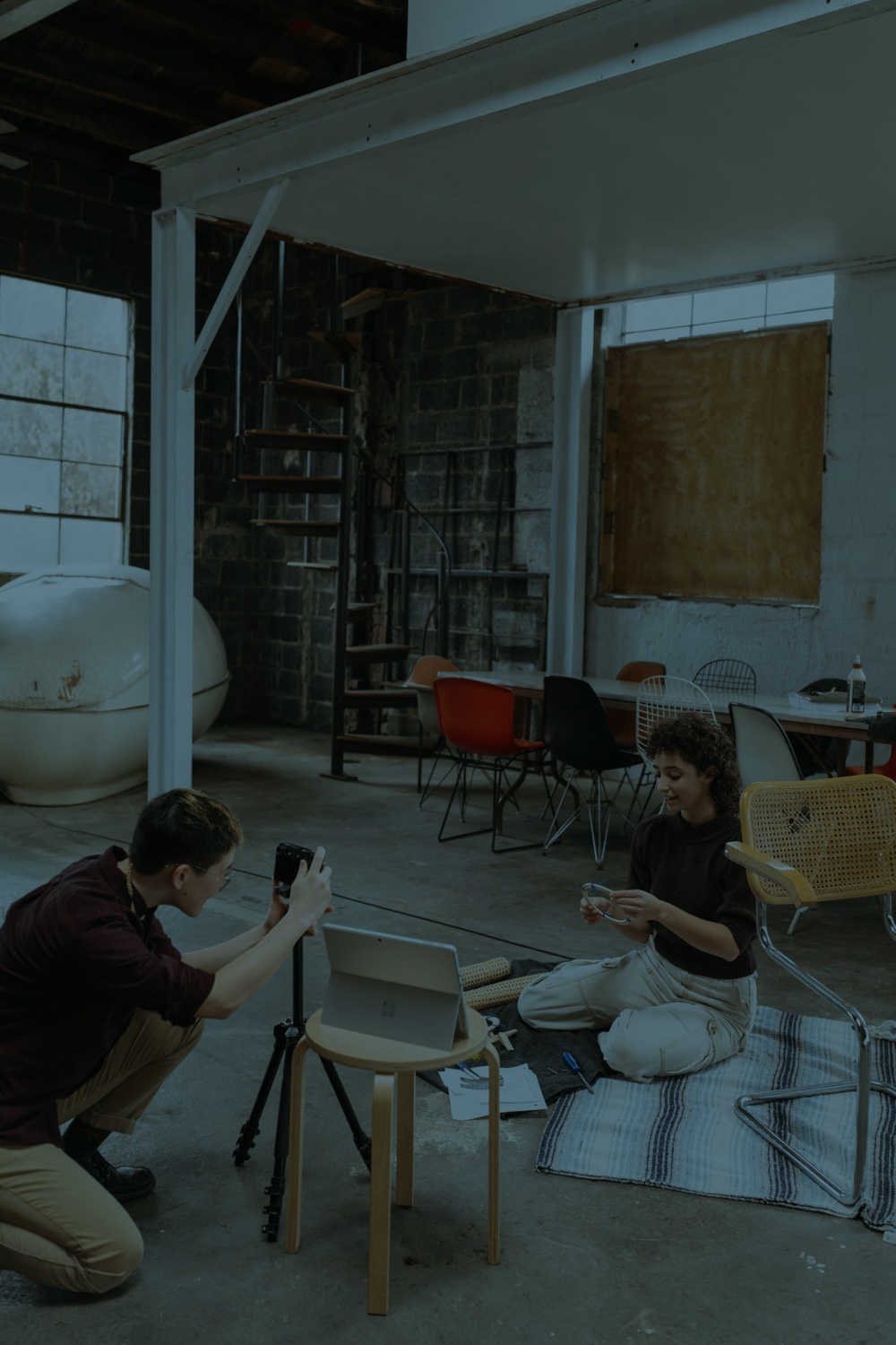 Photograph of two people in a loft working on a craft project with cameras and laptops.